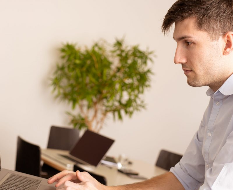 das Bild zeigt einen Mann der an einem Laptop arbeitet