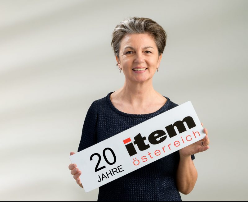das Bild zeigt eine Frau mit einem 20 Jahre item österreich Schild